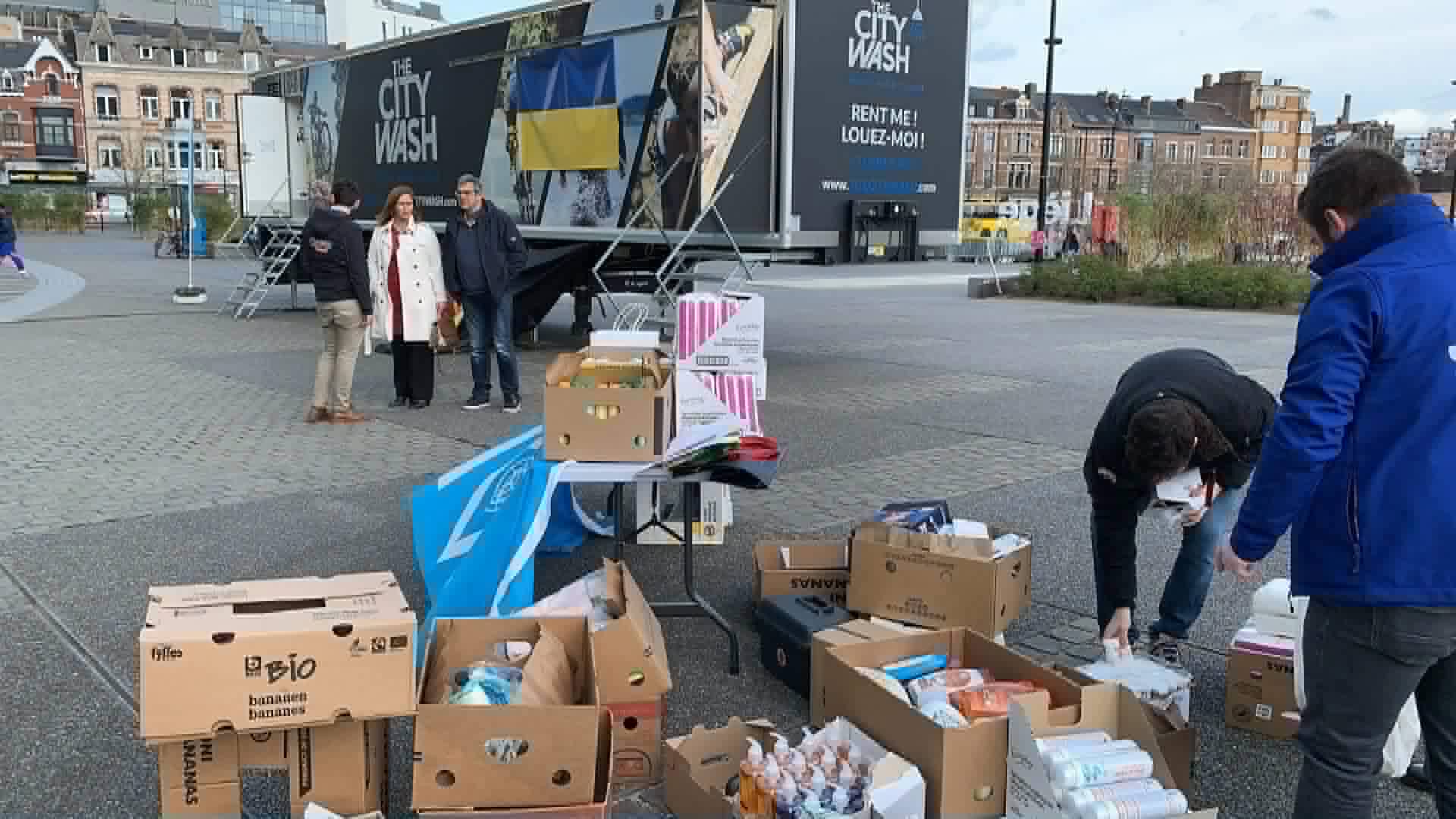 Donated hygiene products in boxes in front of a mobile shower truck with a Ukrainian flag, before its trip to Romania